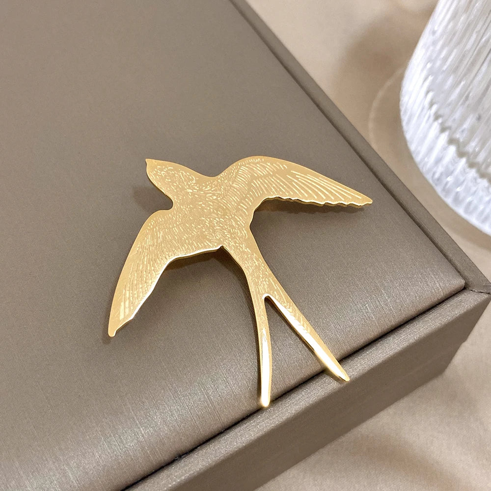Gold bird-shaped object on a beige surface