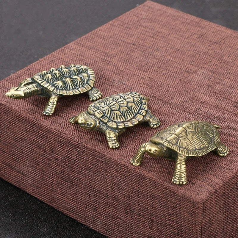 Three bronze turtle figurines on a textured brown surface