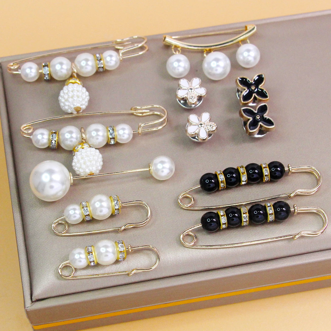 Adjustable pearl safety pins for clothing styling on beige surface