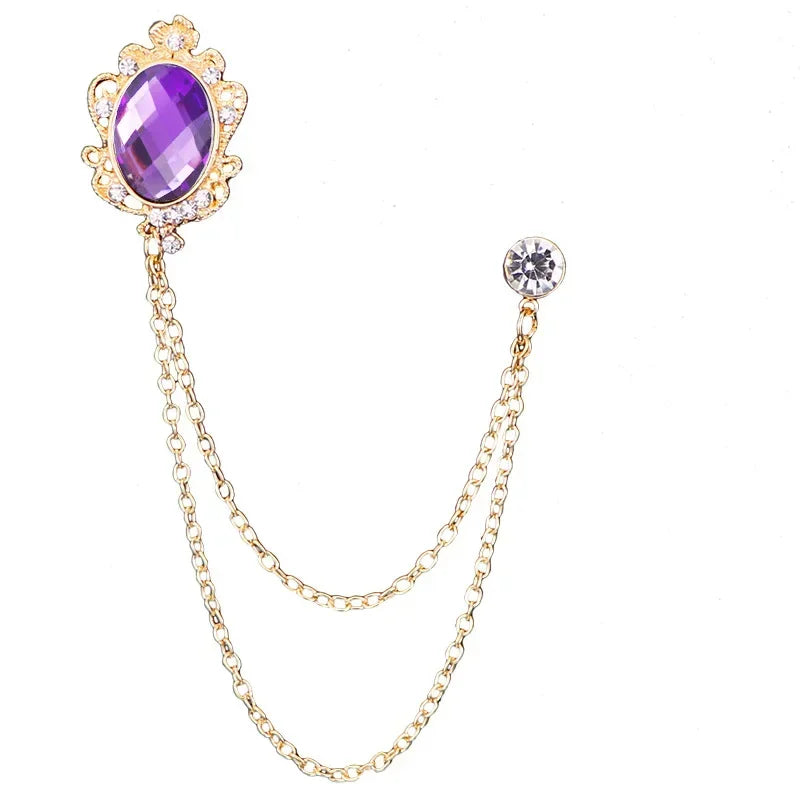 Gold brooch with a purple gemstone and chain on a white background