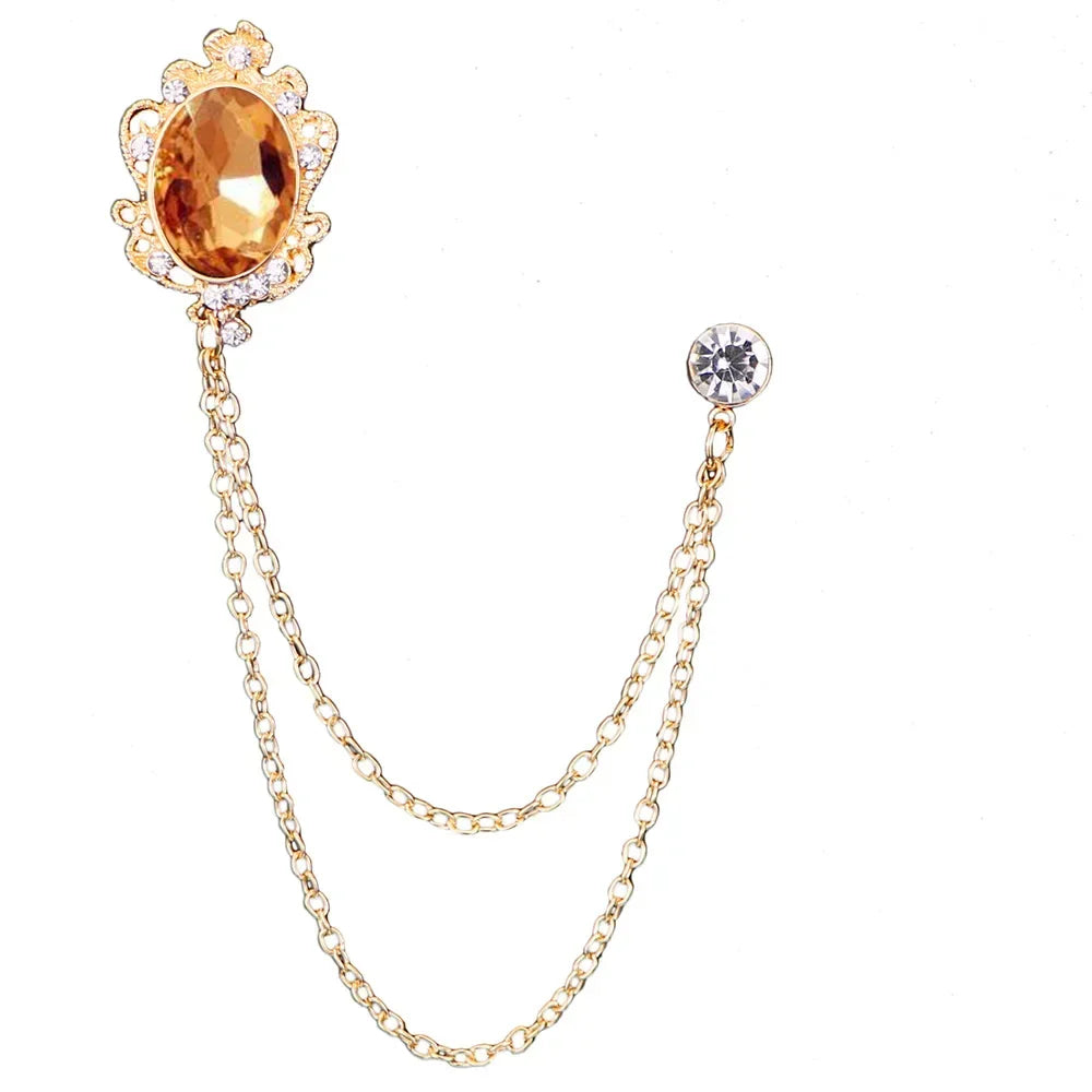 Gold brooch with a large amber-colored gemstone and a smaller gemstone on a white background