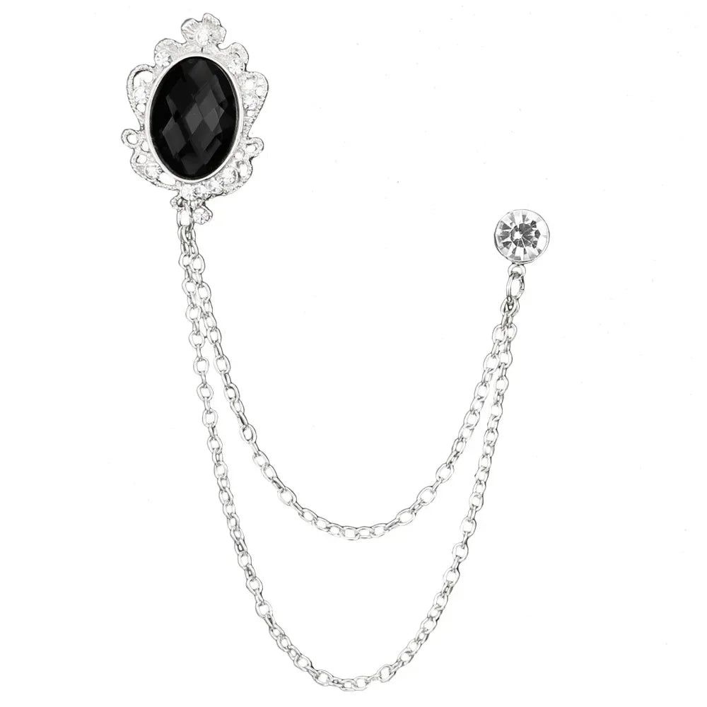 Silver brooch with black gemstone and chain on a white background
