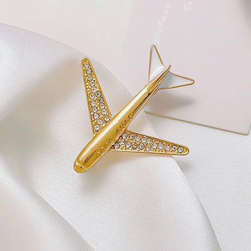 Gold airplane shaped rhinestone brooch luxury aviation fashion accessory on white background