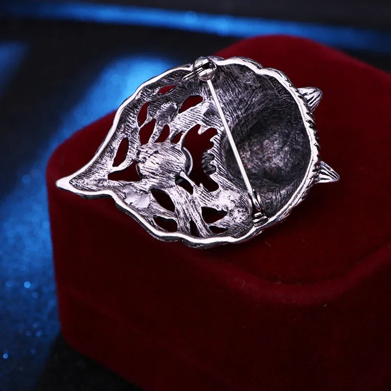 Silver brooch on a red cushion with a dark background