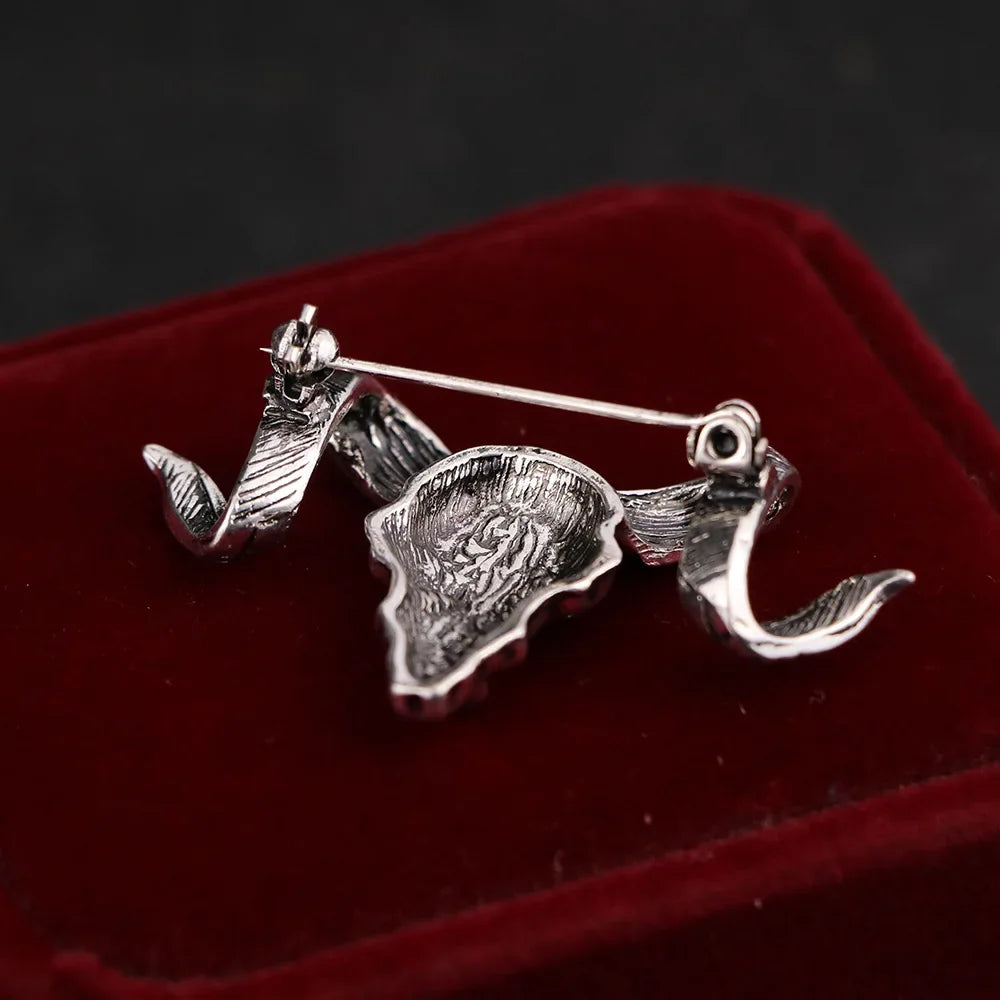 Silver ram skull brooch showcased on a premium velvet display surface.