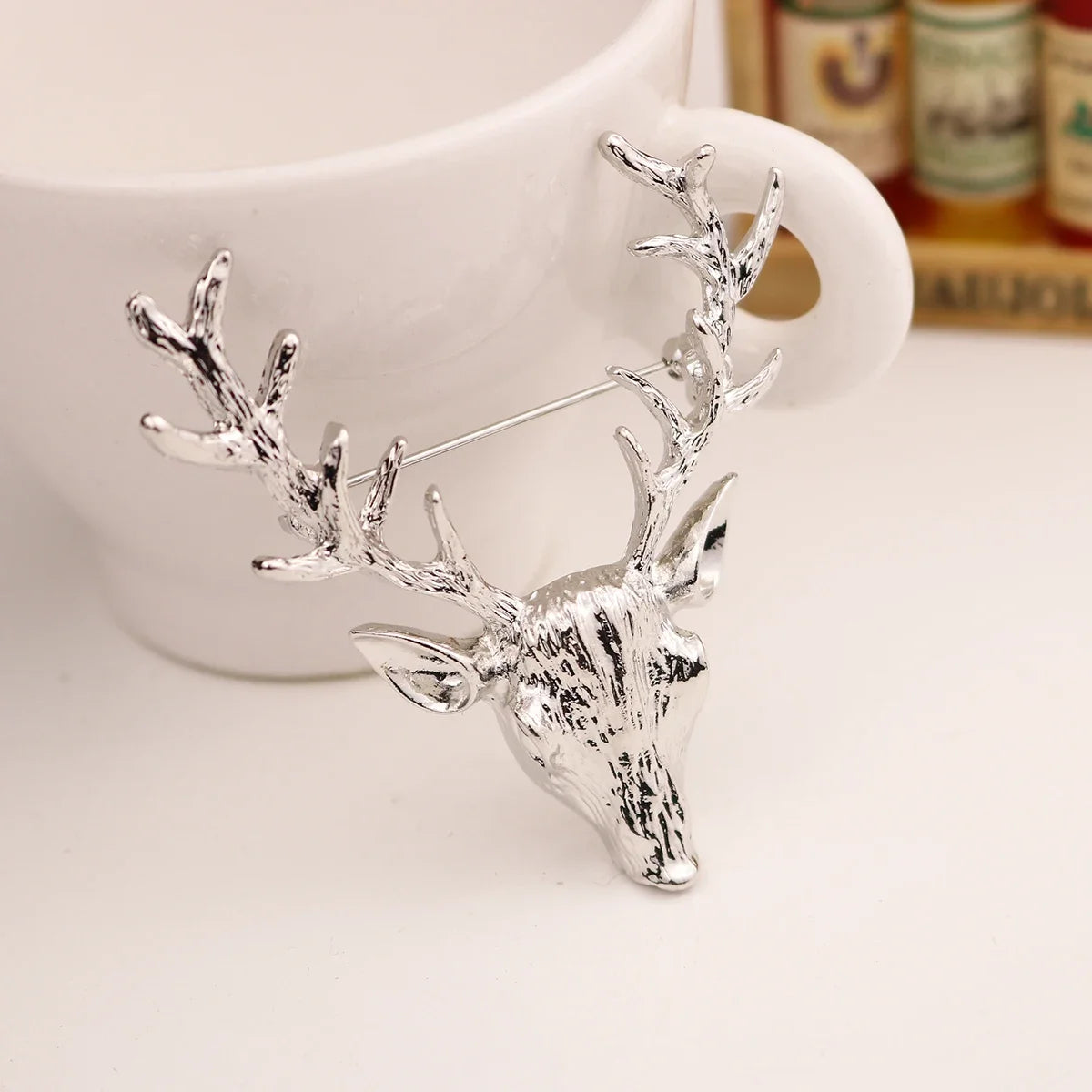 Silver deer head brooch on a white background