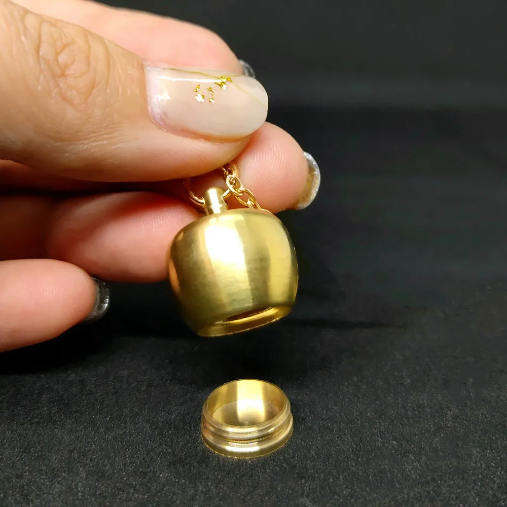 Vintage gold apple pendant with hidden storage compartment held in hand against dark background