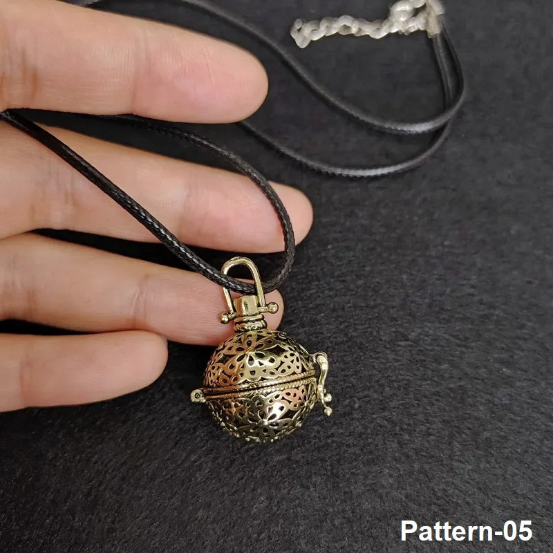 Bronze pendant on a black cord held by a hand against a dark background