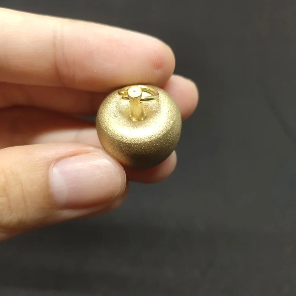 Frosted gold apple-shaped keepsake pendant with brass finish displayed in hand
