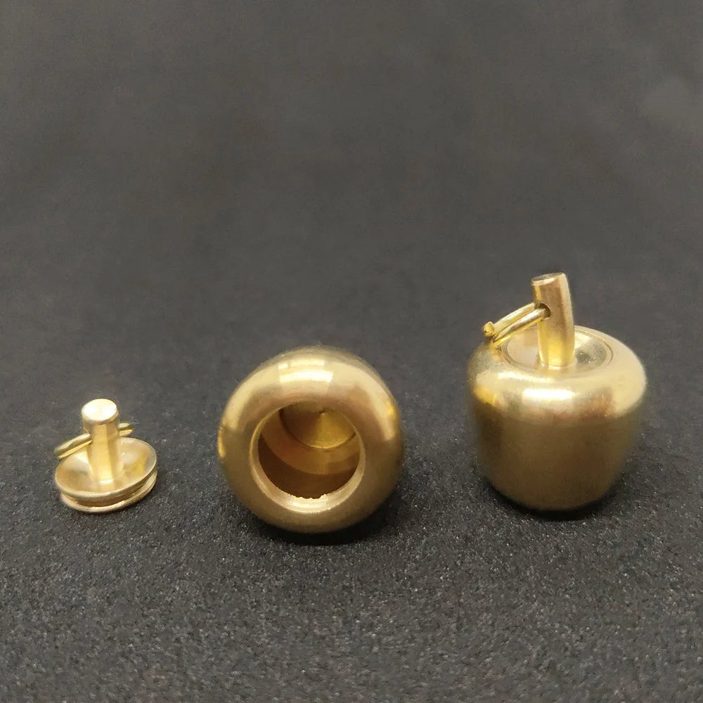 Brass apple urn pendant components showing screw lock closure and storage chamber