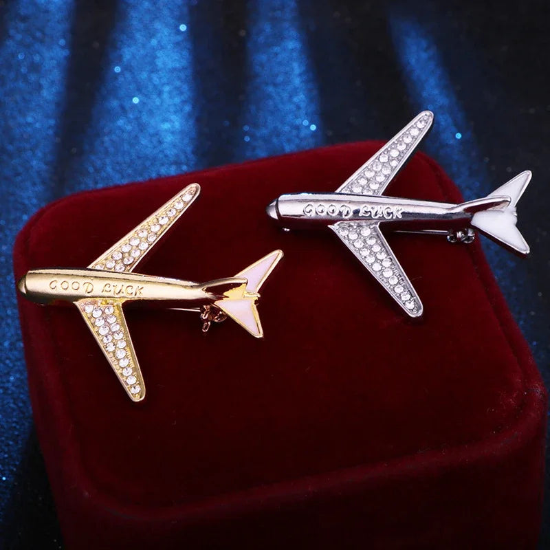 Gold and silver airplane shaped jewelry pieces on red cushion luxury fashion accessory display