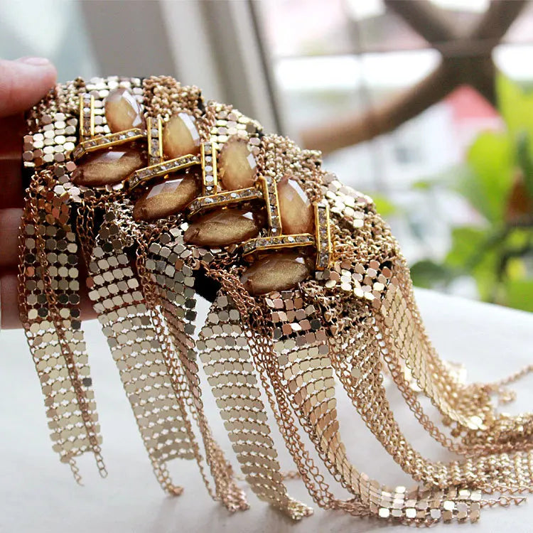 Luxury tassel shoulder epaulette brooch held in hand against blurred background.