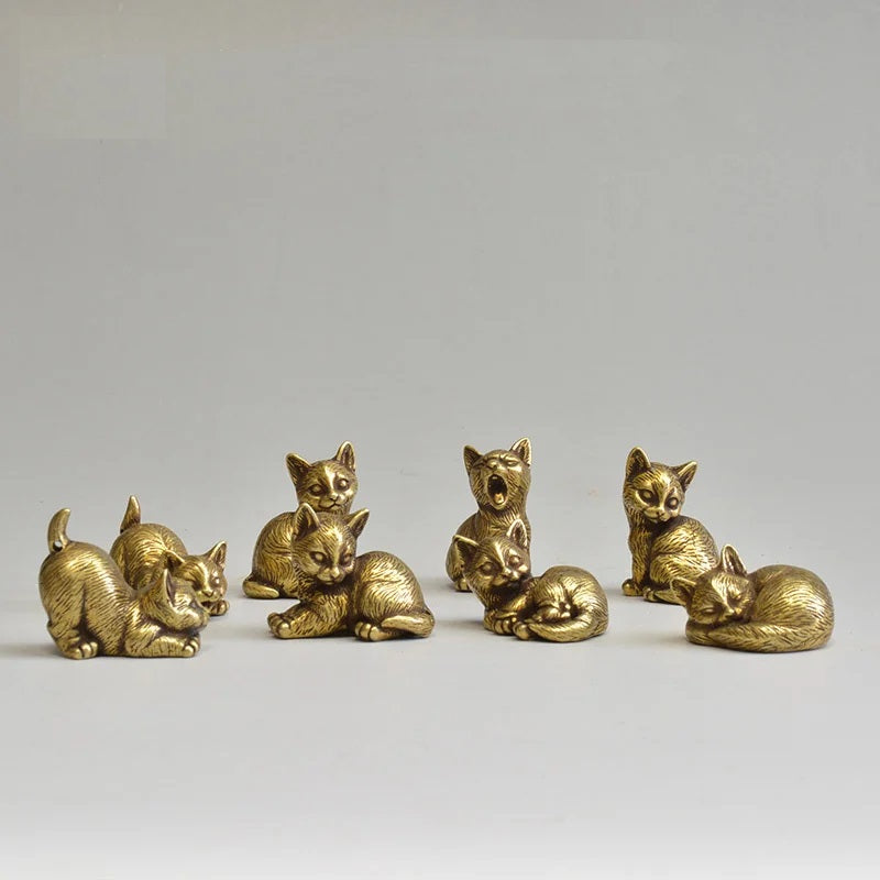 Set of six small gold cat figurines on a light gray background