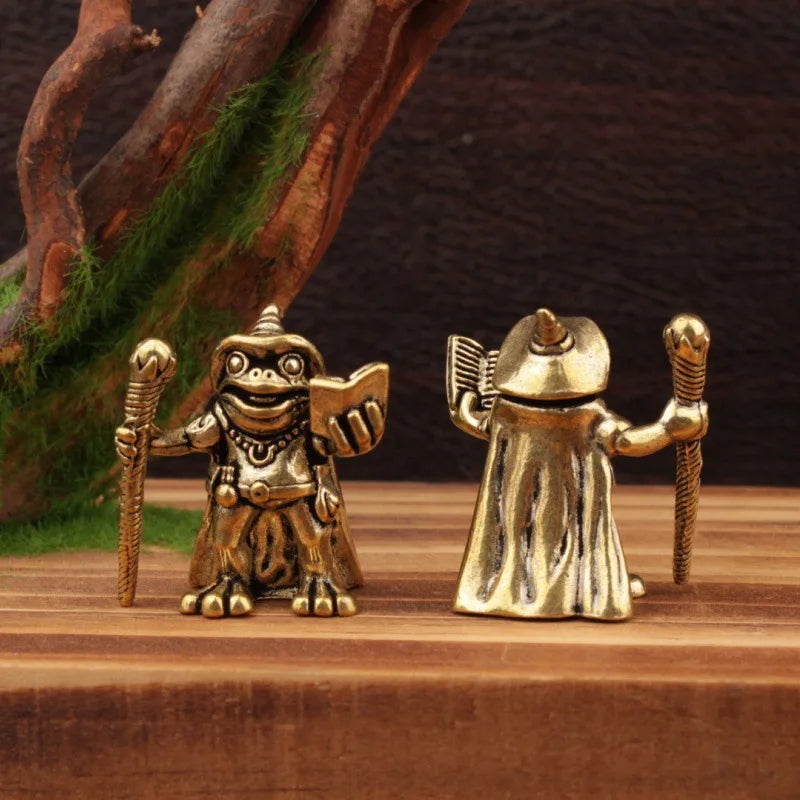 Two gold frog figurines on a wooden surface with a natural background