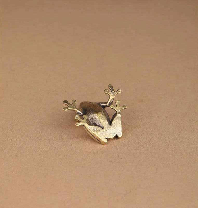 Bronze frog figurine on a beige background