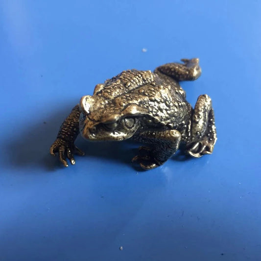 Solid brass lucky toad figurine on blue background for home and desk decor