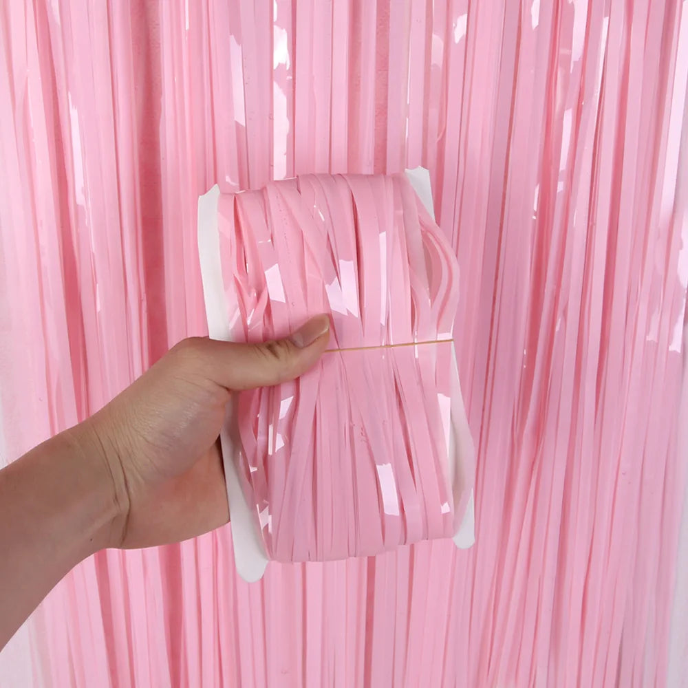 Hand holding a pink decorative bow against a pink tinsel curtain