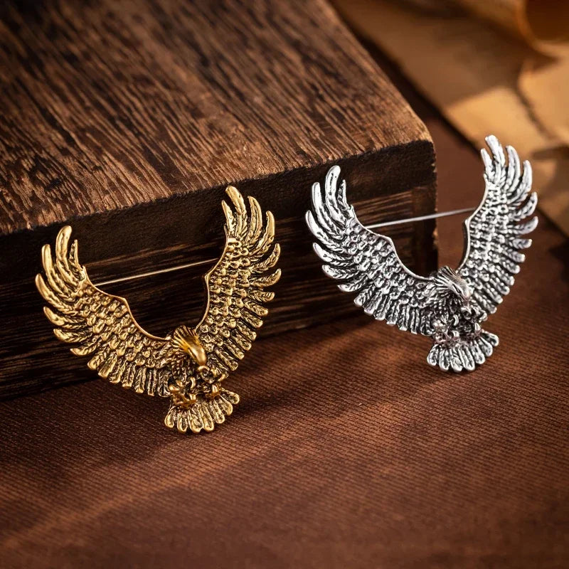 Gold and silver eagle brooch collection on wooden surface
