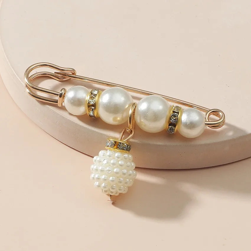 Elegant pearl brooch with gold detailing on beige background
