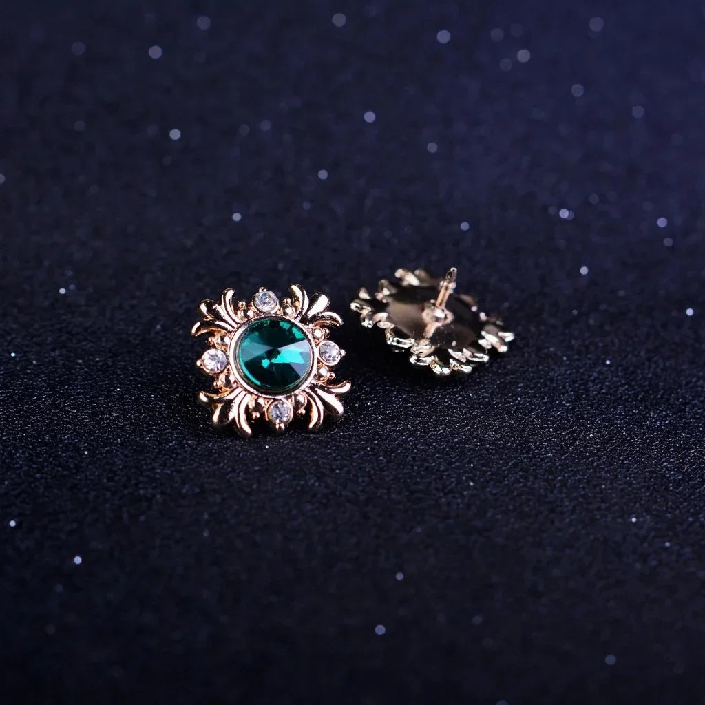 Gold brooch with green gemstones on a dark background