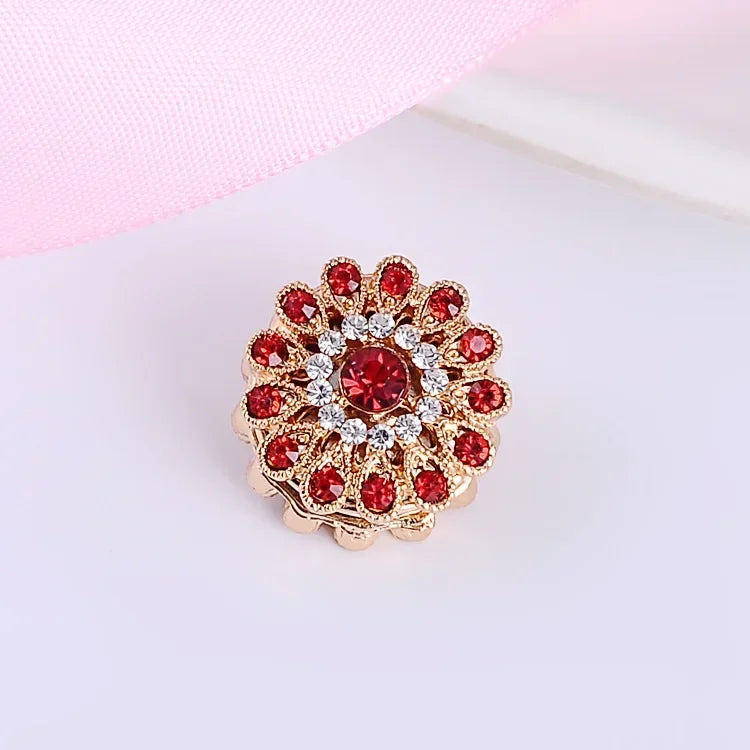 Floral rhinestone magnetic scarf brooch with red stones and gold finish on a light pink background