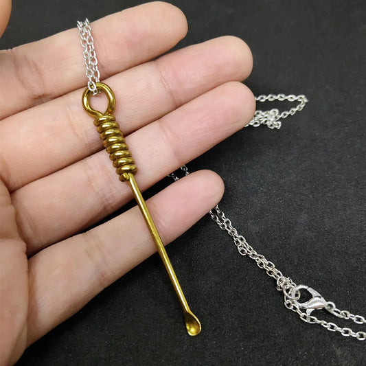 Gold and silver mini spoon pendant necklace displayed on a dark background with detailed metal craftsmanship