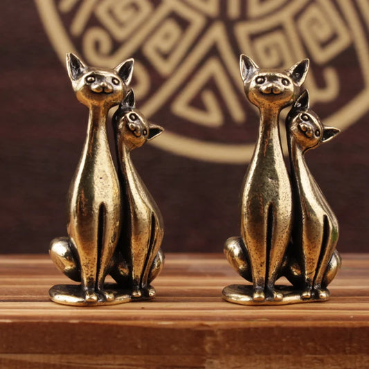 Cute couple cat brass figurine displayed on a wooden surface with decorative vintage background
