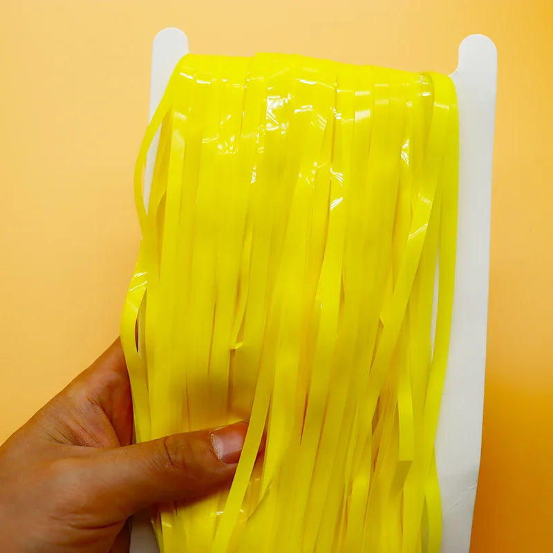 Yellow tassels held by a hand against an orange background