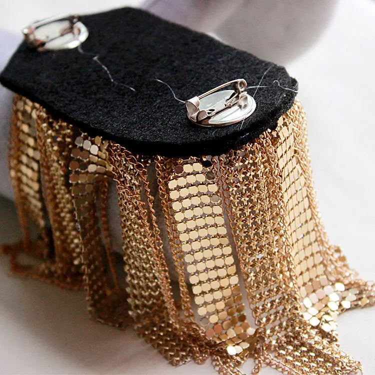 Rhinestone shoulder epaulette brooch displayed on black fabric background.