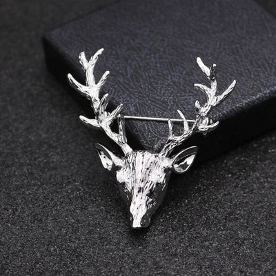 Silver deer head brooch on a dark textured background