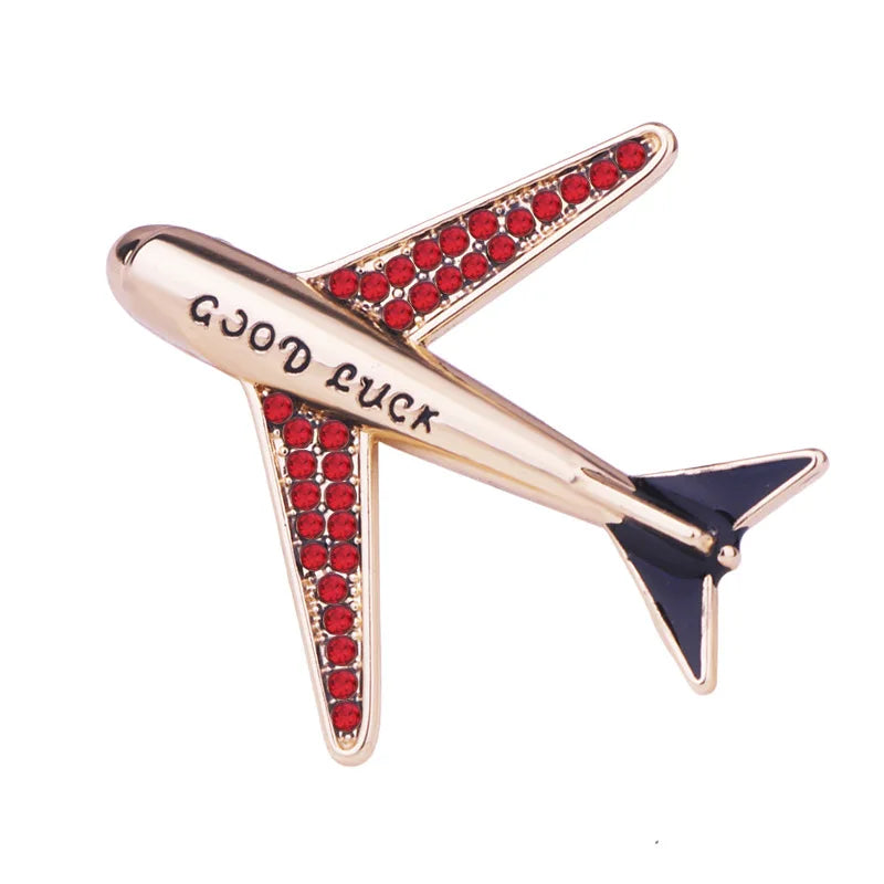 Gold aircraft brooch pin with gemstone details on white background.