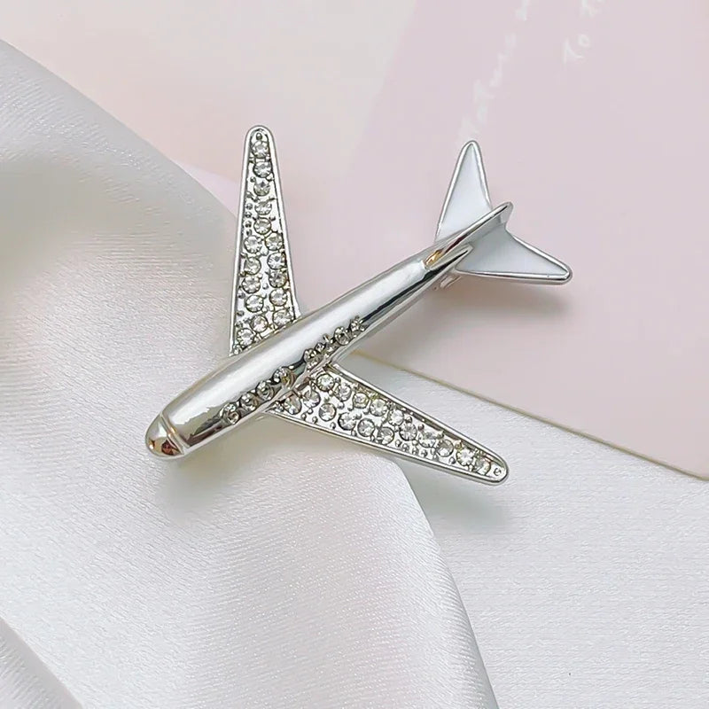 Silver airplane brooch with gemstones elegant aircraft lapel pin on white fabric background