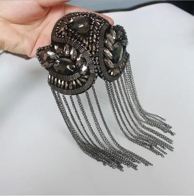 Luxury gemstone tassel brooch held in hand on white background