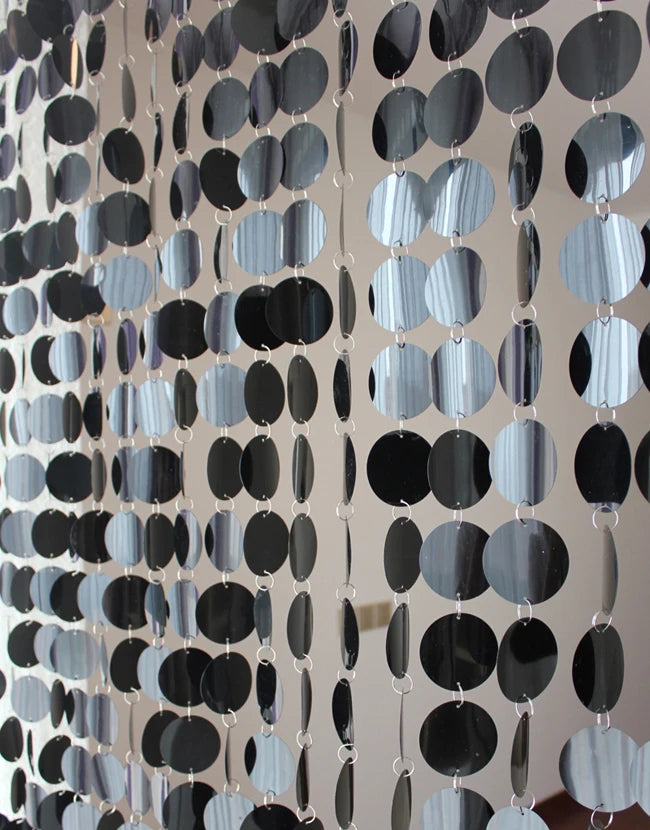 Decorative string curtain with black and gray oval beads on a neutral background