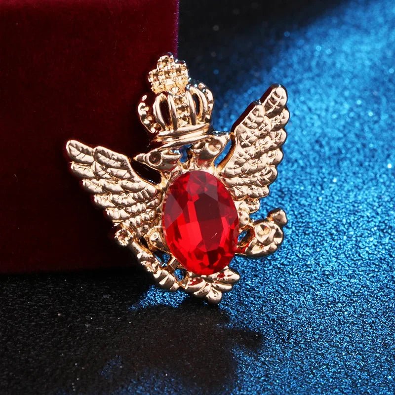 Gold angel brooch with red gemstone luxury fashion jewelry on blue and red fabric background