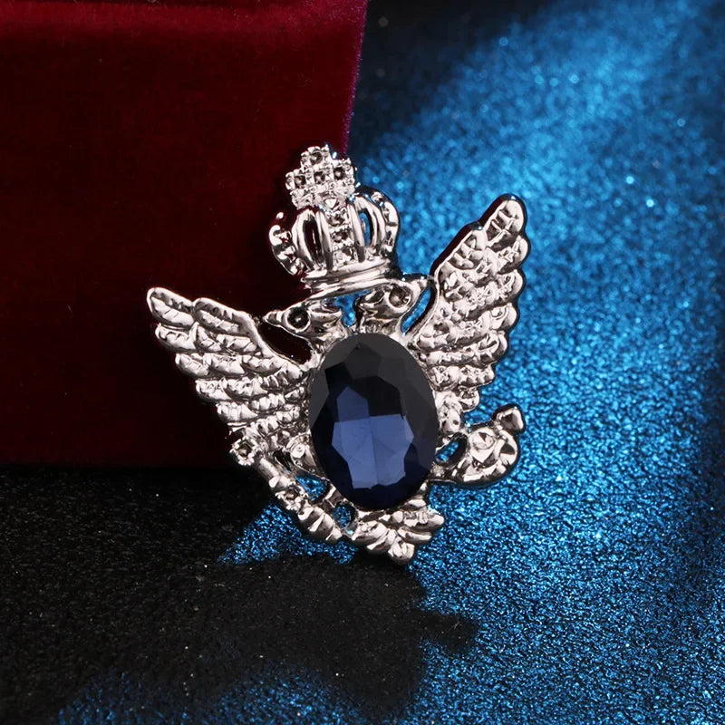 silver angel brooch with blue gemstone luxury fashion jewelry on blue and red fabric background