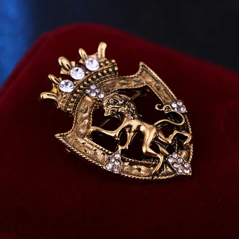 Gold lion brooch with crystal crown design on red cushion