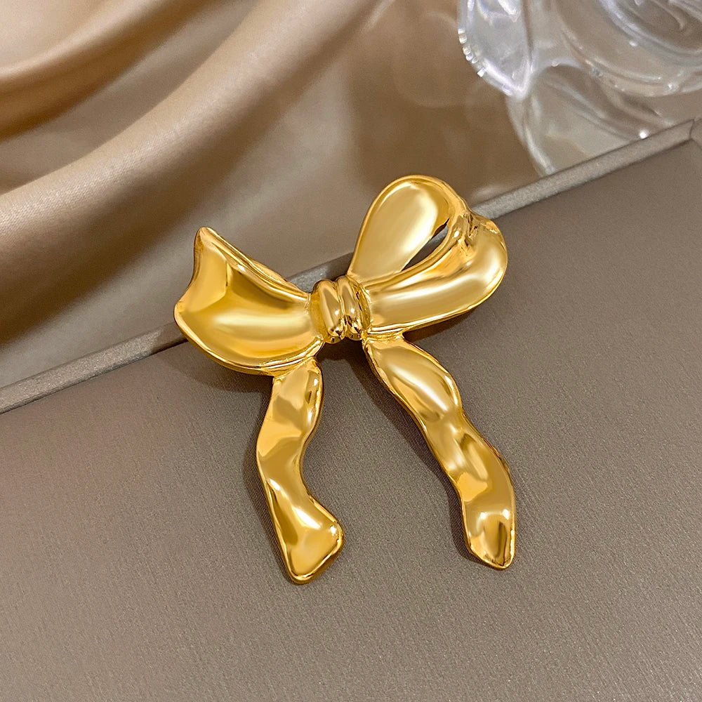 Gold bow-shaped brooch on a neutral background