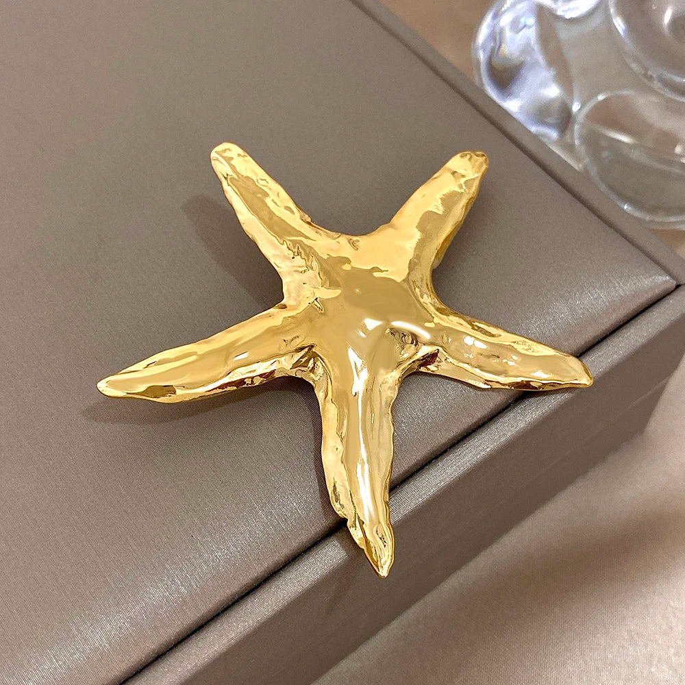 Gold starfish-shaped brooch on a gray surface