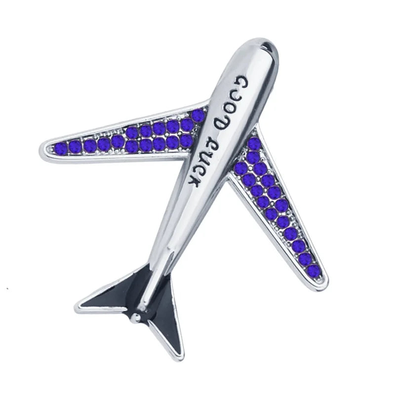 Silver airplane brooch with blue crystal accents on white background.