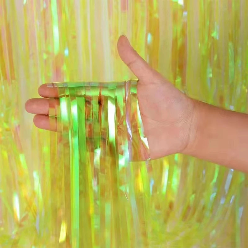Hand holding a transparent plastic strip against a colorful tinsel curtain background