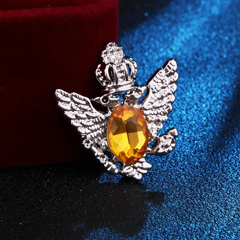 silver angel brooch with yellow gemstone luxury fashion jewelry on blue and red fabric background