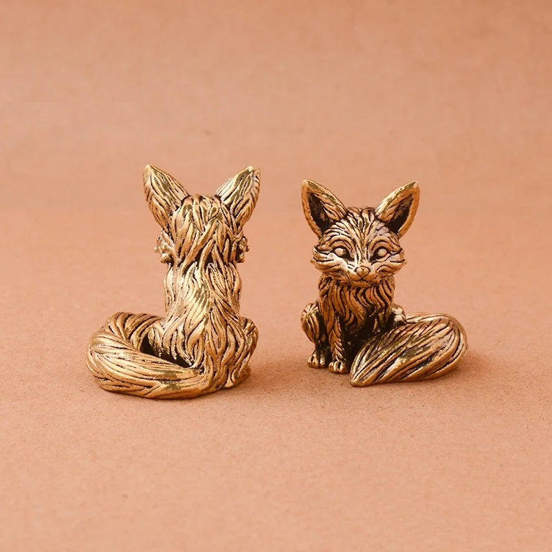 Pair of gold fox figurines on a beige background