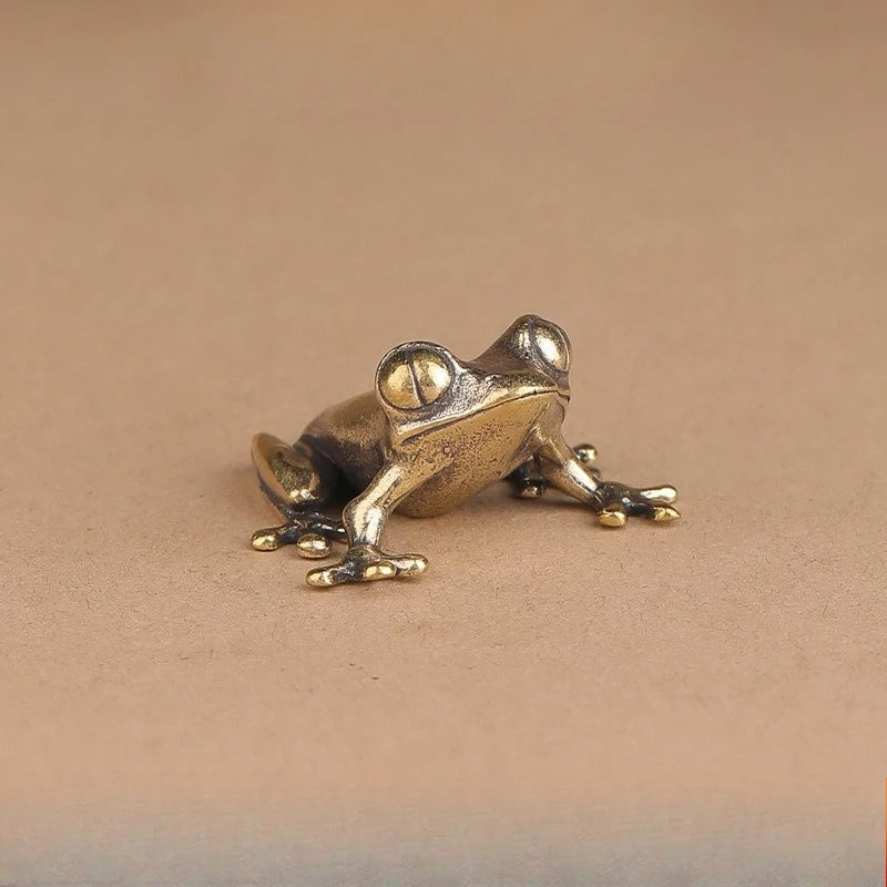 Bronze frog figurine on a beige background