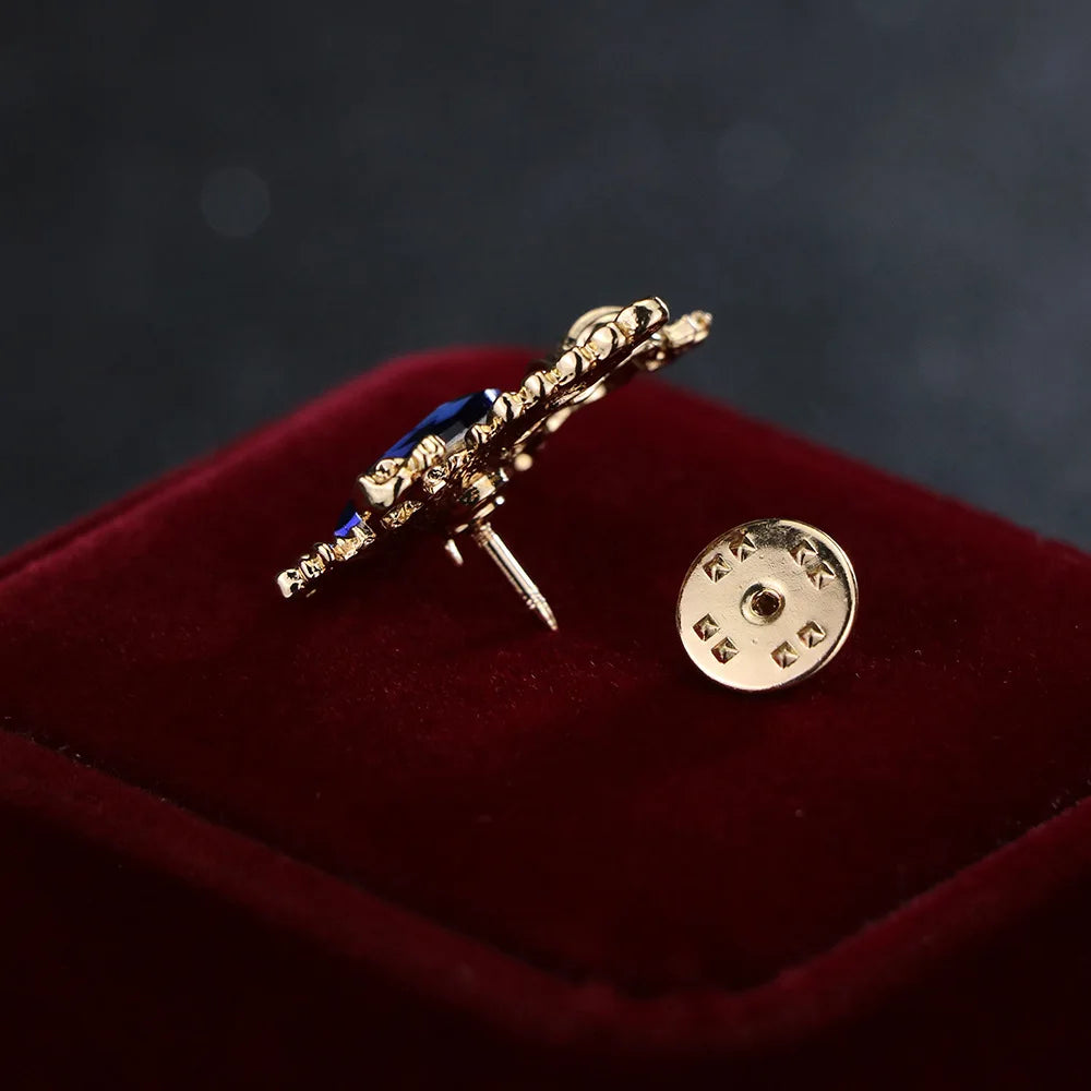 gold angel brooch with blue gemstone luxury fashion jewelry on blue and red fabric background