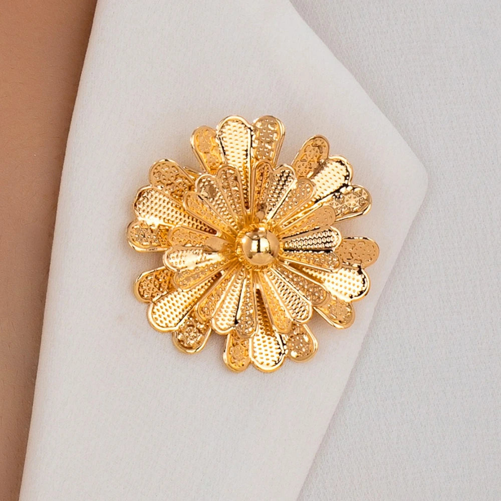 Gold floral brooch on a white fabric background