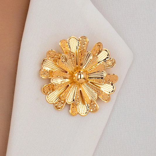 Gold floral brooch on a white fabric background