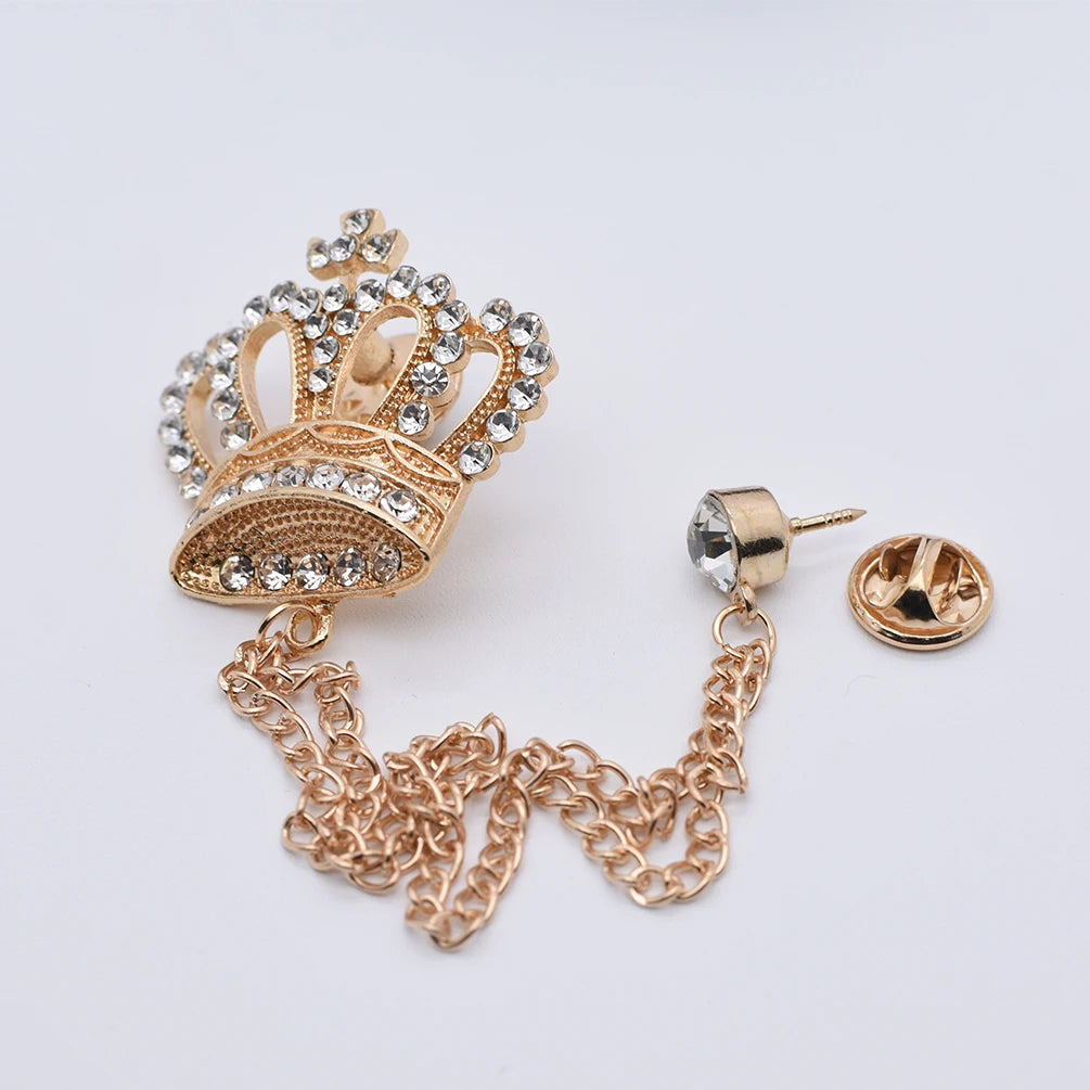 Gold crown-shaped brooch with chain on a white background