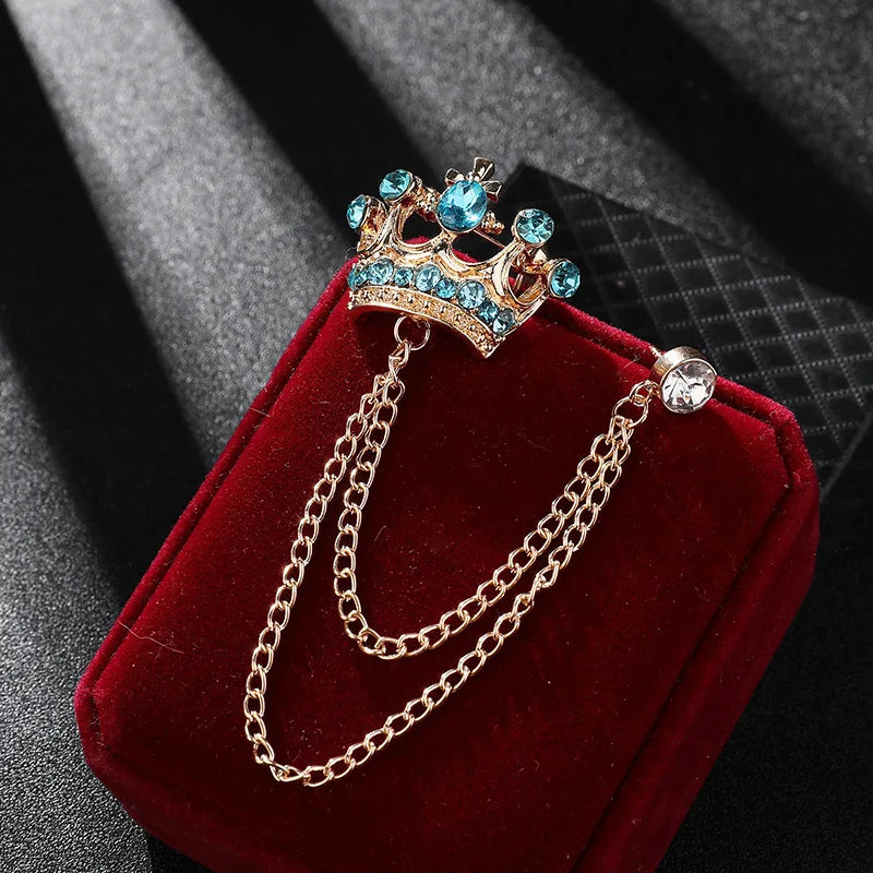 Decorative brooch with crown design on a red cushion against a dark background