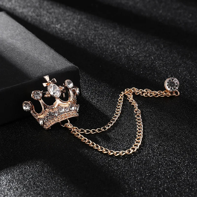 Crown-shaped brooch with chain on a dark surface
